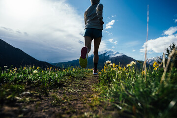 Trail runner running on the high altitude grassland mountain top trail