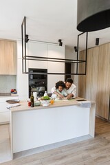 A father talks while holding a rolling pin with his daughter while they roll out the dough and...