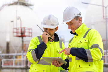 Engineers team, workers in a refinery - oil processing equipment and machinery energy factory. Image of engineers put hands on top of each others as symbol of their partnership. 