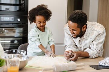 The father laughs and watches as his daughter gathers flour