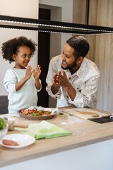 A father and his daughter applaud and look at each other while he smiles