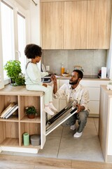 The daughter is sitting on the table and gives a fork to the father who is sitting next to her and...