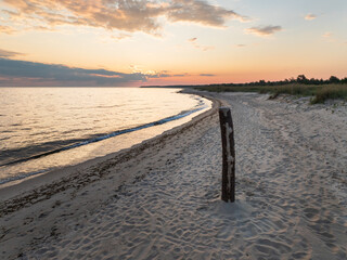 Aerial drone view of the scenic sandy beach coast of the Baltic Sea in Perakula, Estonia during a tranquil sunset.