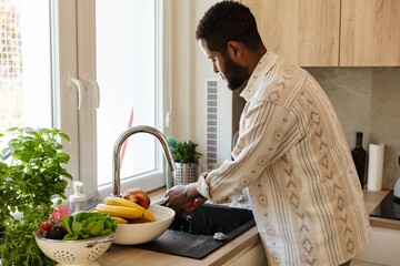 The father stands and washes his hands in the sink