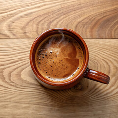 Fresh coffee in brown cup on wooden table top view