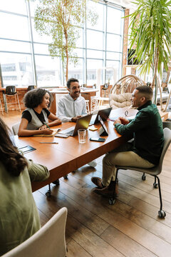 Fototapeta A group of three workers are smiling and talking while sitting at a table