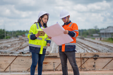 Construction engineer inspecting railway track industrial documents in hand while examining rail structure closely construction, safety and professional project management transportation development.