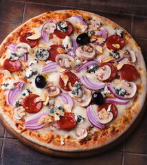 Pizza with chorizo ​​sausage, mozzarella cheese, and black olives. Rustic wooden background. Soft focus.	