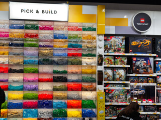 Obraz premium Colorful Lego bricks display at a toy store with shoppers and a family