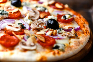 Pizza with chorizo ​​sausage, mozzarella cheese, and black olives. Rustic wooden background. Soft focus.	