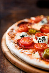 Pizza with chorizo ​​sausage, mozzarella cheese, and black olives. Rustic wooden background. Soft focus.	