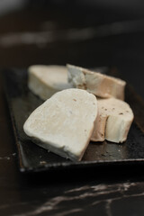 Gourmet French foie gras delicacy is elegantly presented on a luxurious black marble slate. This fine dining appetizer highlights rich texture against the striking dark stone background