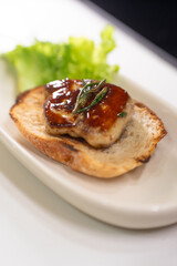 Seared French foie gras, a gourmet delicacy, is beautifully plated on toasted bread with fresh vegetable garnish, highlighting the dish's richness on a clean white plate