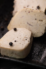 Seared foie gras delicacy, generously seasoned with coarse black pepper, creating a visually striking and rich texture contrast, ready for fine dining enjoyment