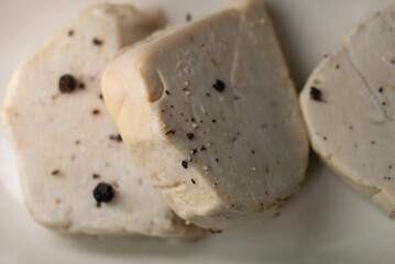 Raw French foie gras block seasoned with whole black peppercorns, ready for gourmet preparation and cooking, emphasizing a culinary process