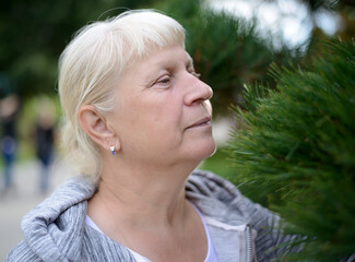 Aged woman exploring nature among greenery.
