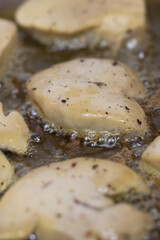 Seared foie gras sizzling in a hot frying pan with rendered fat, creating a golden-brown crust for a classic French gourmet cooking process