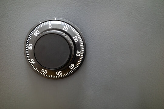 A close-up of limb a safe black combination dial set against a gray door. Focus is on precision and secure access.