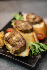 Elegant seared foie gras on toasted bread, served with a side of savory roasted vegetables including vibrant tomatoes and garlic