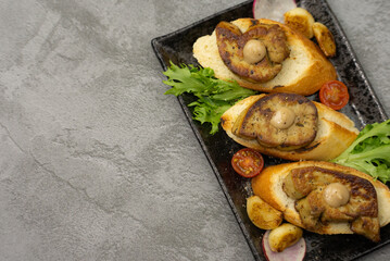 Delicious seared foie gras on toasted bread, garnished with savory roasted vegetables, including tomatoes, and aromatic garlic