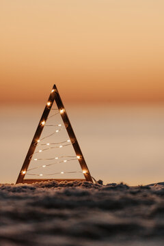 Boho driftwood Christmas tree illuminated with micro fairy lights on a beach in Australia.  Muted hues