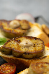 Delicious seared foie gras on toasted bread, garnished with savory roasted vegetables, including tomatoes, and aromatic garlic