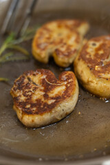 Sizzling pan-seared foie gras with fresh thyme sprigs in a hot skillet, creating a rich, aromatic French gourmet delicacy