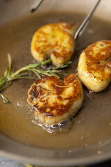 Sizzling pan-seared foie gras with fresh thyme sprigs in a hot skillet, creating a rich, aromatic French gourmet delicacy
