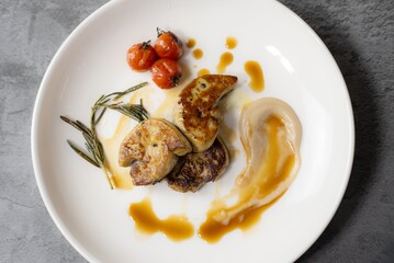 Elegant Gourmet Dish: Succulent Seared Foie Gras with Roasted Tomato and Thyme, Served with a Rich, Exclusive Specialty Sauce on a White Plate