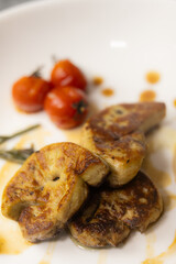 Elegant Gourmet Dish: Succulent Seared Foie Gras with Roasted Tomato and Thyme, Served with a Rich, Exclusive Specialty Sauce on a White Plate