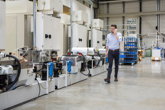 Businessperson talking on mobile in modern production facility