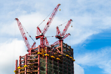 Low-angle view of cranes and steel structures of building construction with a blue sky background in Taiwan.