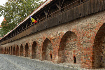 A fragment of the old defensive walls in the Romanian city of Sibiu. The Romanian flag.