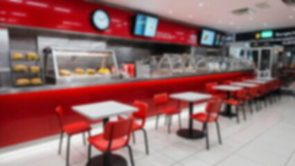 Blurred background of a burger shop in a modern airport, there are tables and chairs neatly lined up for visitors to sit.