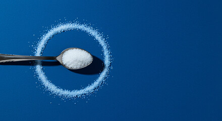 Spoon with sugar casting circular shadow on blue background for World Diabetes Day
