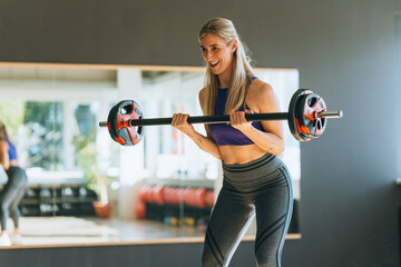 Fit woman in sportswear training muscles with weights showing strength energy motivation and active...