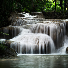 Obraz premium Serene waterfall cascading water tropical forest lush green smooth stream natural rock tranquil pool long exposure jungle scene pristine nature flows gently over terraced rock soothing layers