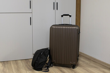 Upright spinner suitcase placed near a freshly made hotel bed with soft daylight. Useful for...
