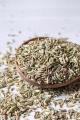 Closeup of Fennel Seed Heap in a Wooden Spoon Isolated on White Background with Copy Space in Vertical Orientation
