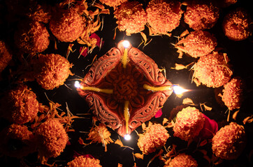 Top View of Deepavali or Diwali Festival Clay Diya with Oil and Glowing Flames with Marigold Flower Petals on Black Background with Copy Space, Happy Diwali or Deepavali Festival Celebration Concept