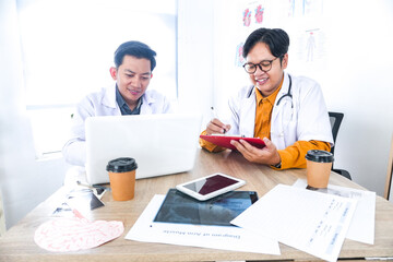 Two Young Doctors Collaborating With Technology and Charts at Modern Office Desk