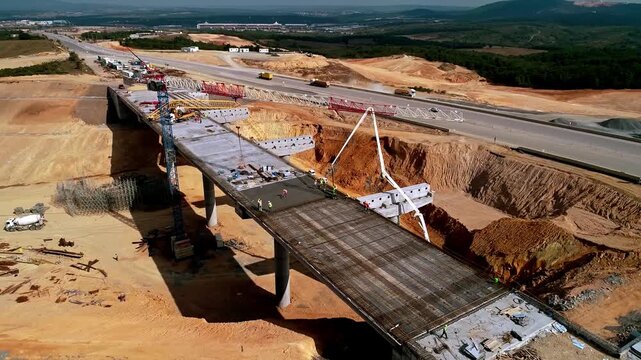 Drone footage of bridge and highway construction site with concrete work, steel structures, and heavy equipment. Large-scale infrastructure and civil engineering project.