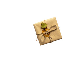 A beautifully wrapped gift with twine and autumn leaves on a stark, black background
