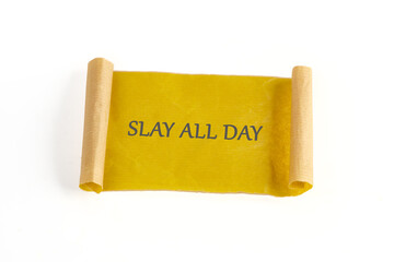 A decorative scroll made of yellow paper unfurls to reveal the bold phrase encouraging individuals to slay all day. This inspiring piece radiates positivity and empowerment