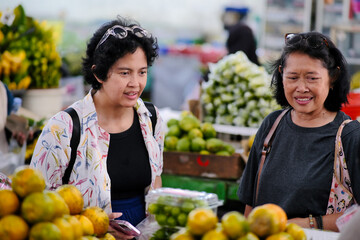 Two women buying some fresh fruits in the local market