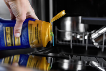 A woman pouring gel into the dishwasher.
