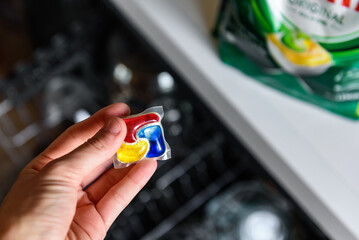 Woman putting detergent capsule into dishwasher.