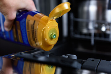 A woman pouring gel into the dishwasher.