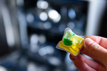 Woman putting detergent capsule into dishwasher.