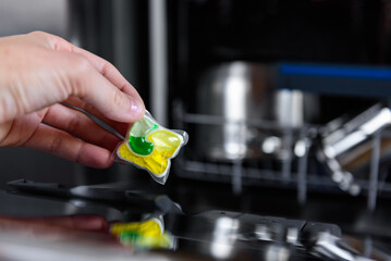 Woman putting detergent capsule into dishwasher.